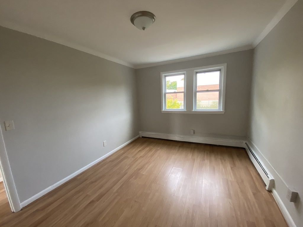 157-167 Delhi Street Boston, MA 02126 - Photo 14 of 16 an empty room with wooden floor and windows