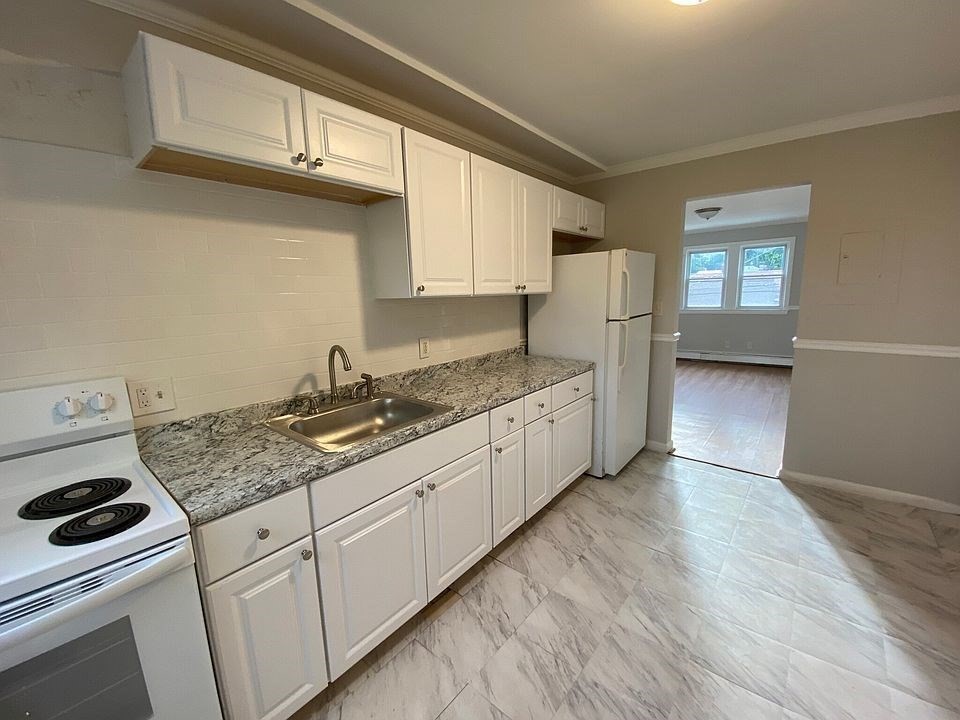 157-167 Delhi Street Boston, MA 02126 - Photo 4 of 16 a kitchen with granite countertop white cabinets and white appliances