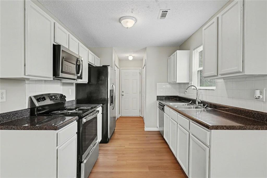 85 Homestead Place Rex, GA 30273 - Photo 6 of 17 a kitchen with stainless steel appliances granite countertop a sink stove microwave and cabinets