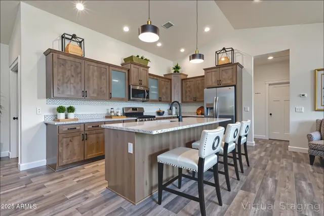 a kitchen with stainless steel appliances granite countertop a kitchen island a stove a sink a refrigerator and a cabinets