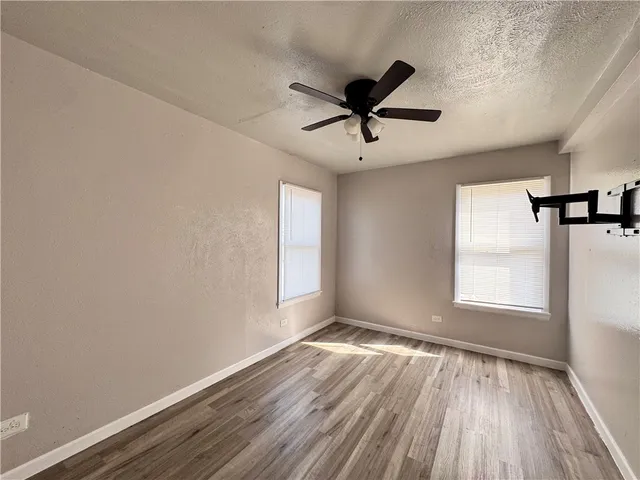 a view of empty room with wooden floor and fan