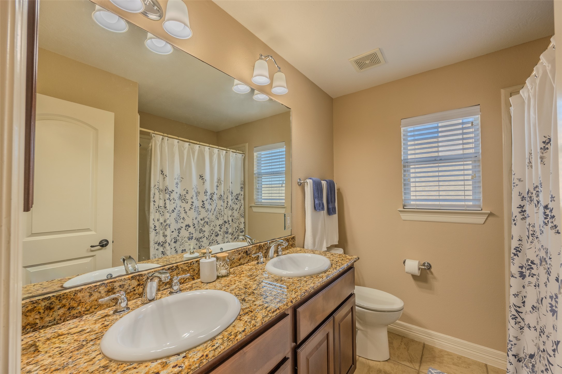 1905 Rosenbaum Drive Brenham, TX 77833 - Photo 25 of 30 a bathroom with a granite countertop sink a mirror a toilet and a window