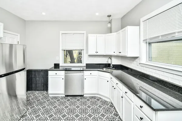 a kitchen with stainless steel appliances granite countertop a sink a stove a refrigerator and white cabinets