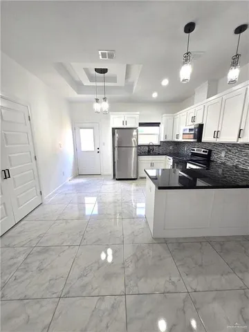 a large kitchen with kitchen island a stove a sink a counter top space and cabinets