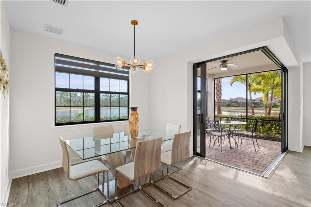 9637 Montelanico Loop, Unit 104 Naples, FL 34119 - Photo 8 of 45 Dining room featuring a water view, a chandelier, wood finished floors, and a ceiling fan