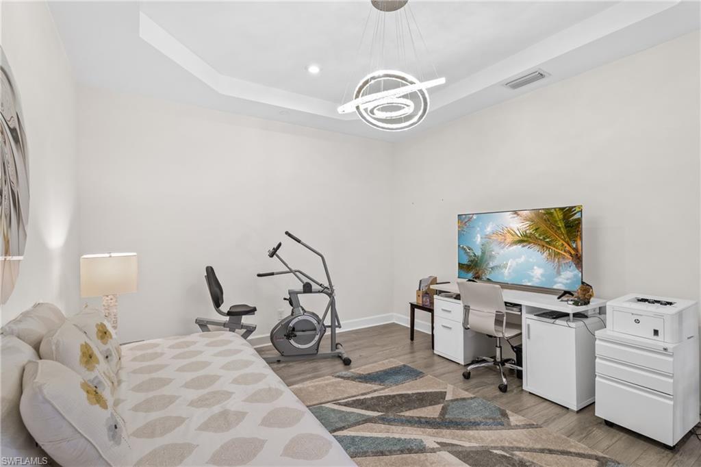 9637 Montelanico Loop, Unit 104 Naples, FL 34119 - Photo 15 of 45 Bedroom with a tray ceiling, light wood-style flooring, a desk, and recessed lighting