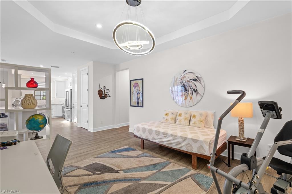 9637 Montelanico Loop, Unit 104 Naples, FL 34119 - Photo 16 of 45 Bedroom with recessed lighting, wood finished floors, freestanding refrigerator, and a tray ceiling