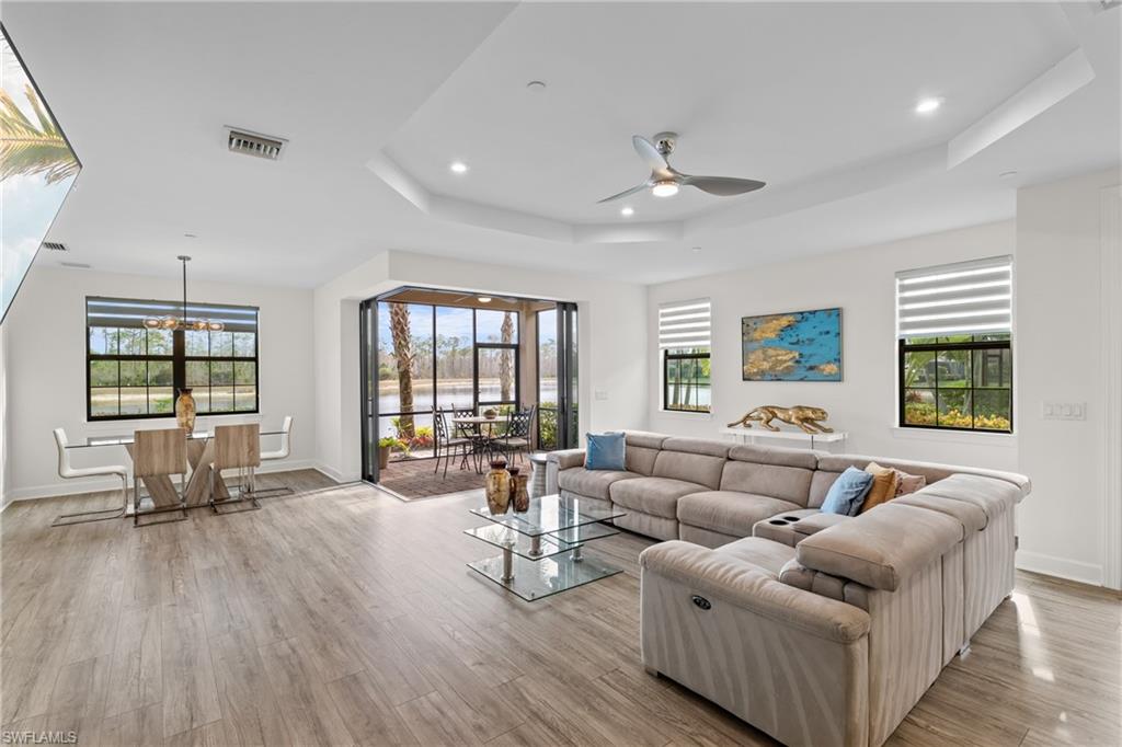 9637 Montelanico Loop, Unit 104 Naples, FL 34119 - Photo 2 of 45 Living room featuring recessed lighting, light wood-style floors, a ceiling fan, a chandelier, and a tray ceiling