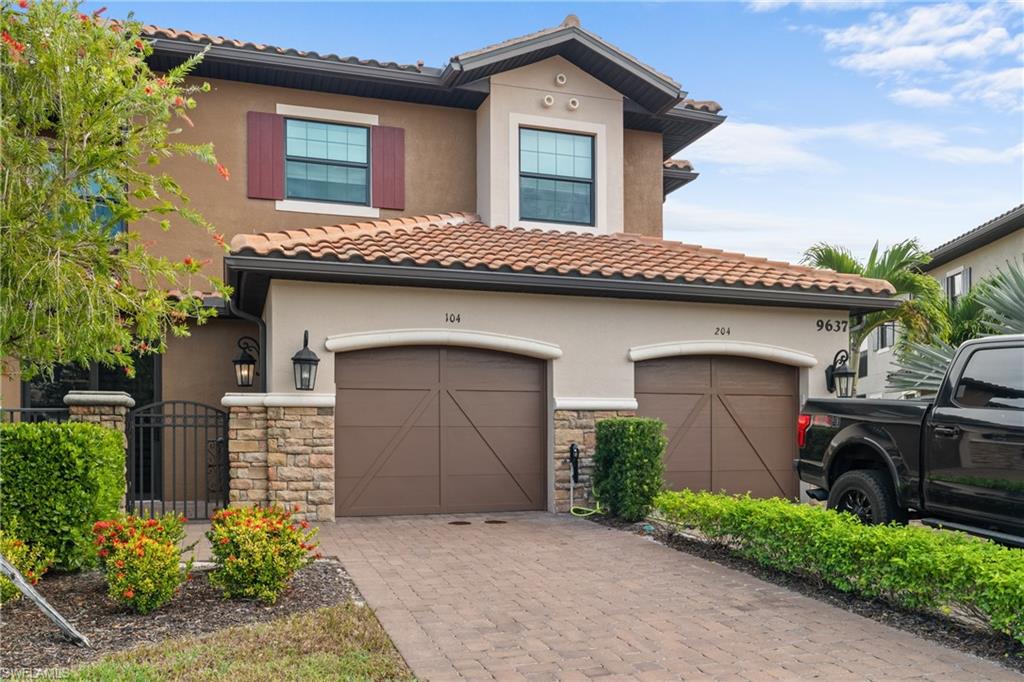 9637 Montelanico Loop, Unit 104 Naples, FL 34119 - Photo 24 of 45 View of front facade with decorative driveway, stone siding, and stucco siding