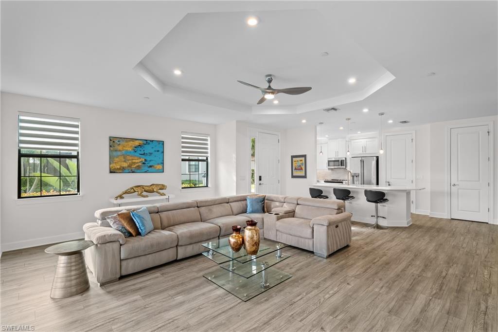 9637 Montelanico Loop, Unit 104 Naples, FL 34119 - Photo 3 of 45 Living room featuring recessed lighting, light wood-type flooring, a ceiling fan, and a raised ceiling