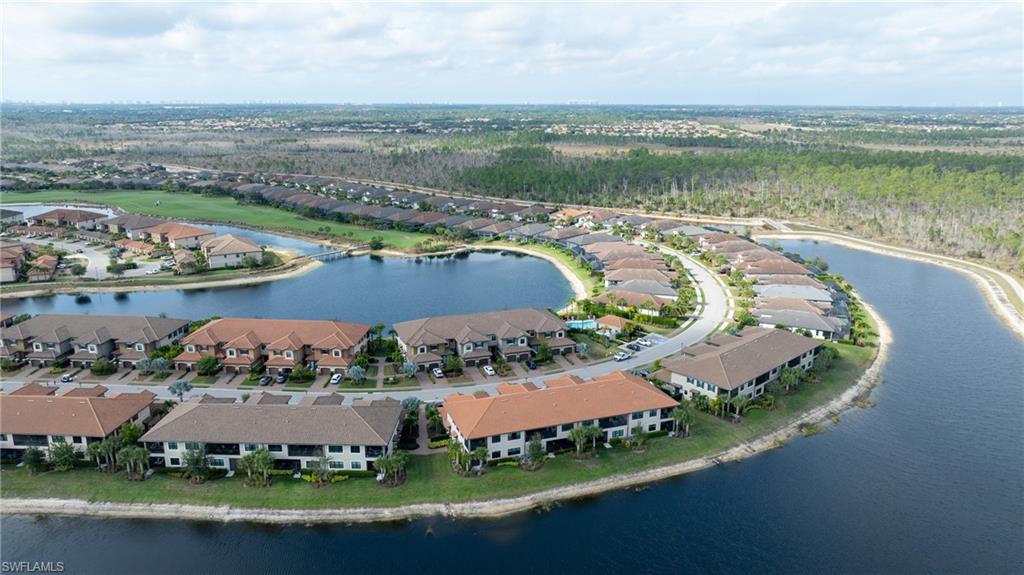 9637 Montelanico Loop, Unit 104 Naples, FL 34119 - Photo 29 of 45 Aerial view of property and surrounding area featuring a large body of water and nearby suburban area