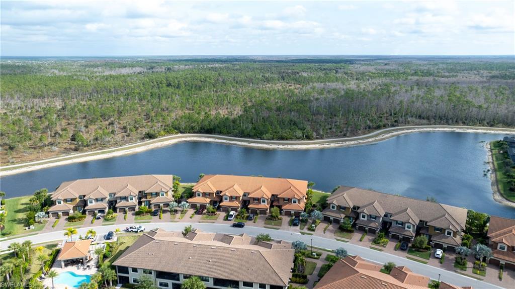 9637 Montelanico Loop, Unit 104 Naples, FL 34119 - Photo 30 of 45 Aerial view of a nearby body of water and a heavily wooded area