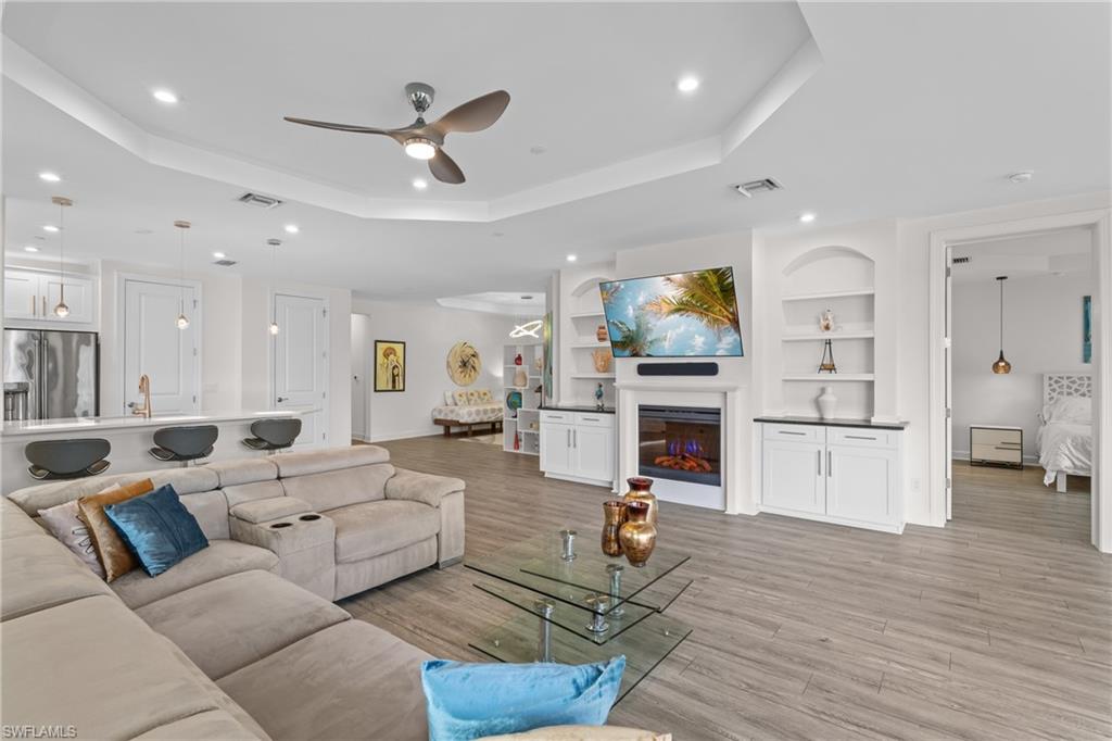 9637 Montelanico Loop, Unit 104 Naples, FL 34119 - Photo 4 of 45 Living area featuring built in shelves, a ceiling fan, recessed lighting, a glass covered fireplace, and light wood-style flooring