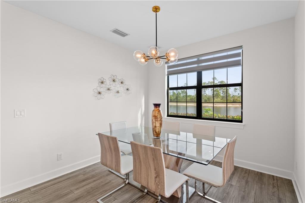 9637 Montelanico Loop, Unit 104 Naples, FL 34119 - Photo 7 of 45 Unfurnished dining area featuring light wood-style flooring, a chandelier, and a water view