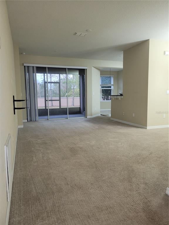 8335 Bella Vida Circle, Unit 8335 Davenport, FL 33896 - Photo 2 of 16 an empty room with windows and view of kitchen
