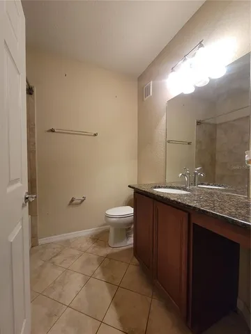 a bathroom with a granite countertop sink a toilet and a mirror