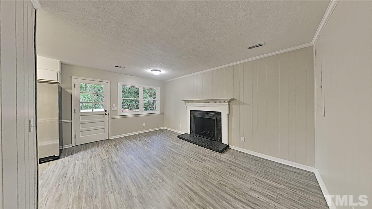 7209 Stuart Drive Raleigh, NC 27615 - Photo 3 of 13 a view of empty room with wooden floor and fireplace