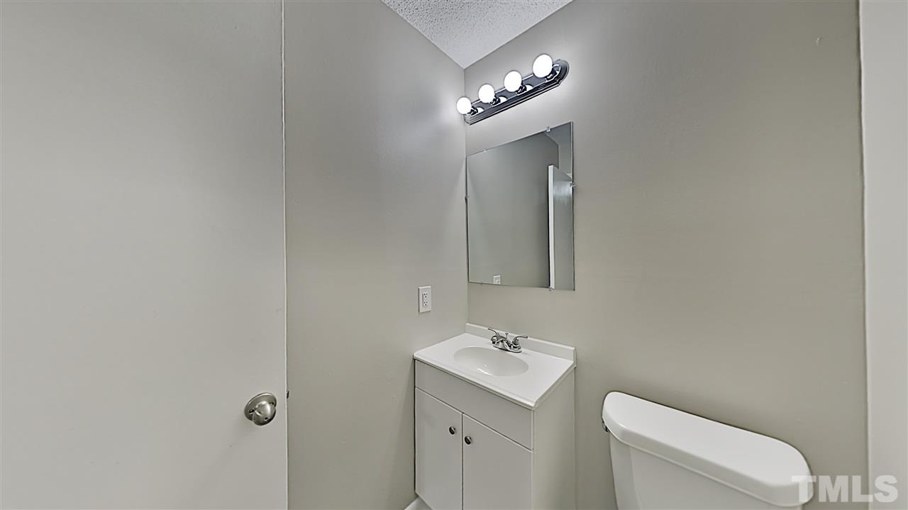 7209 Stuart Drive Raleigh, NC 27615 - Photo 7 of 13 a bathroom with a toilet a sink and mirror