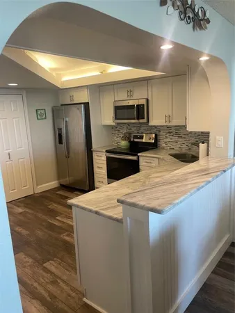 a kitchen with stainless steel appliances kitchen island granite countertop a refrigerator a stove and a sink