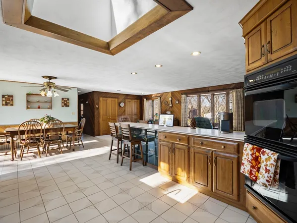 a kitchen with stainless steel appliances granite countertop a stove top oven a sink a dining table and chairs with wooden floor