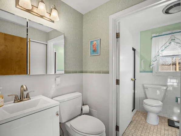 a bathroom with a toilet sink a mirror and vanity