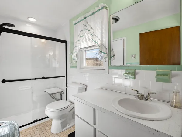 a bathroom with a granite countertop sink mirror vanity and toilet