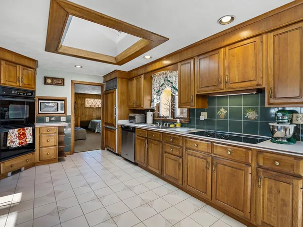 a kitchen with stainless steel appliances granite countertop a refrigerator a sink dishwasher a stove and white cabinets with wooden floor