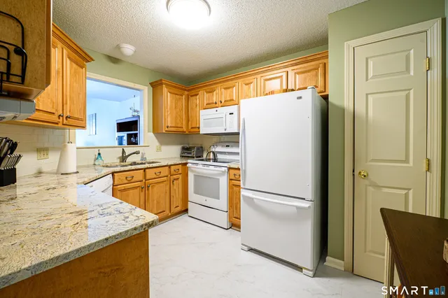 a kitchen with stainless steel appliances granite countertop a refrigerator a stove and a sink with wooden floor