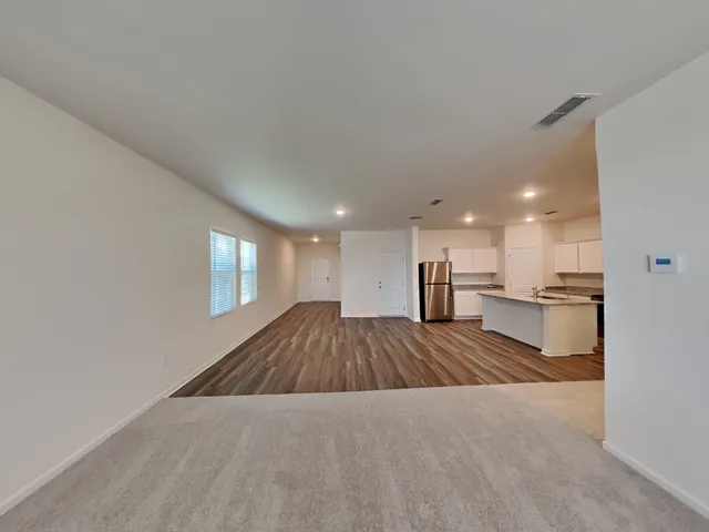 a open kitchen with kitchen island a sink wooden floor and a refrigerator