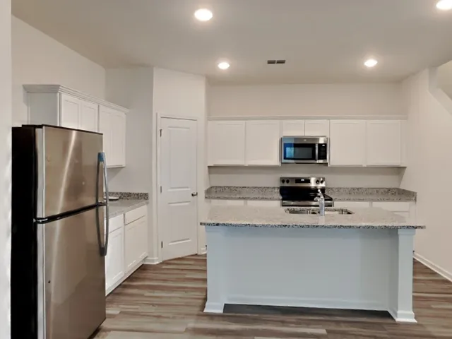 a kitchen with stainless steel appliances granite countertop a refrigerator a stove a sink and a microwave