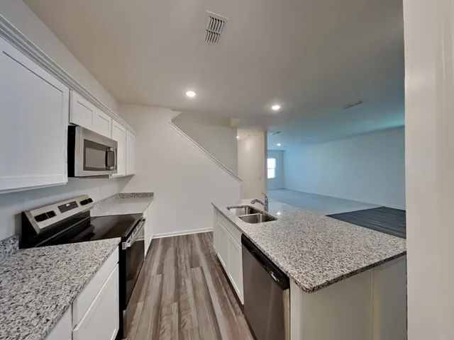 a kitchen with stainless steel appliances granite countertop a sink dishwasher stove and microwave with wooden floor