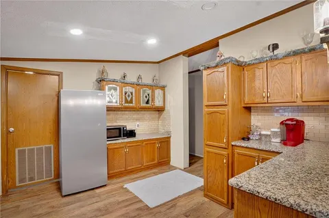 a kitchen with stainless steel appliances granite countertop a refrigerator a stove and a sink with wooden floor