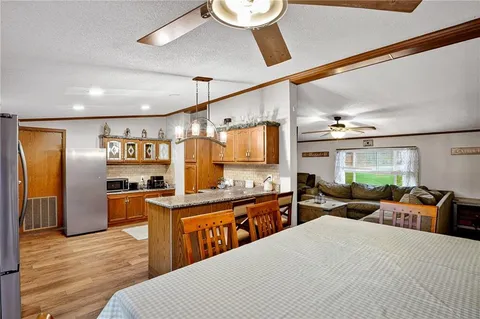 a large kitchen with stainless steel appliances kitchen island granite countertop a refrigerator a sink dishwasher a dining table and chairs with wooden floor