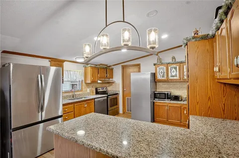 a kitchen with stainless steel appliances granite countertop a refrigerator a stove and a sink