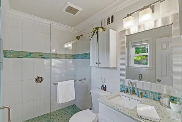 a bathroom with a granite countertop sink a toilet a mirror and shower