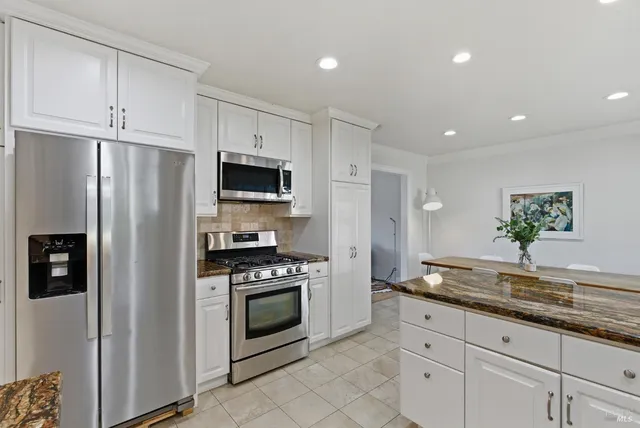 a kitchen with granite countertop a refrigerator stove and microwave