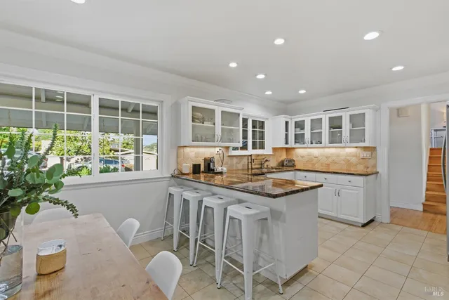 a kitchen with granite countertop a sink and chairs