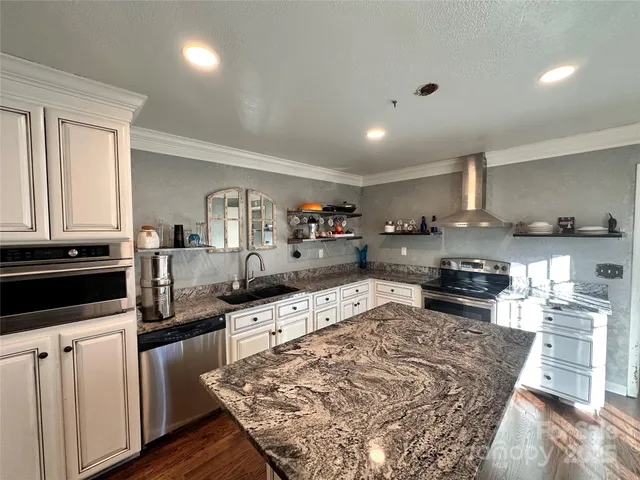 a large kitchen with granite countertop lots of counter space and wooden floor