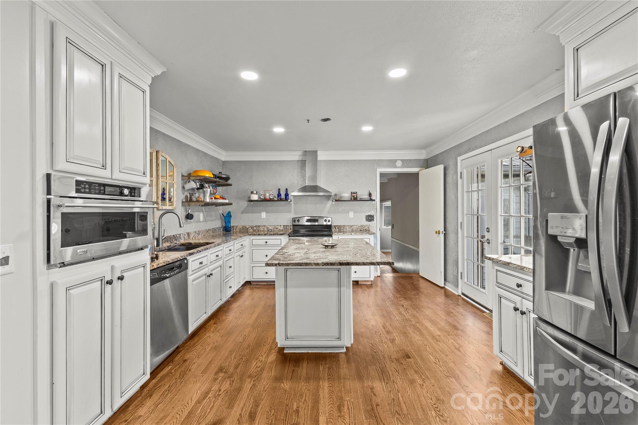 117 Robinson Avenue Matthews, NC 28104 - Photo 9 of 42 a kitchen with stainless steel appliances granite countertop a refrigerator a stove a sink and white cabinets with wooden floor