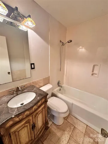 a bathroom with a granite countertop sink a toilet a mirror and shower