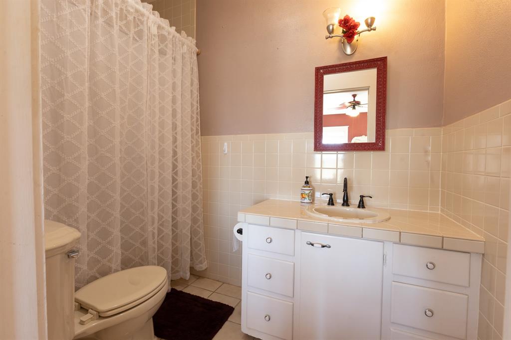 1115 Austin Street Coleman, TX 76834 - Photo 22 of 40 a bathroom with a toilet a sink and a mirror