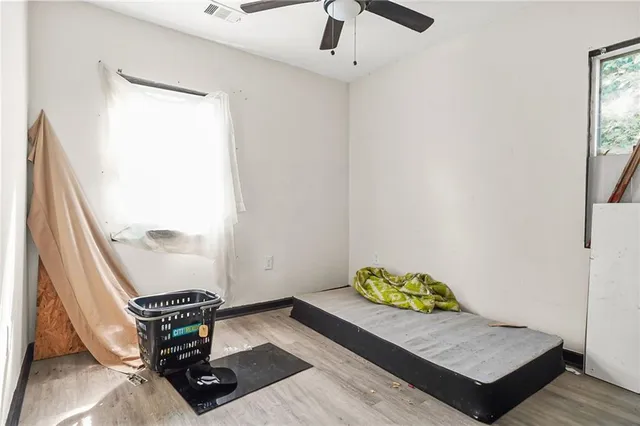 a view of empty room with wooden floor and fan
