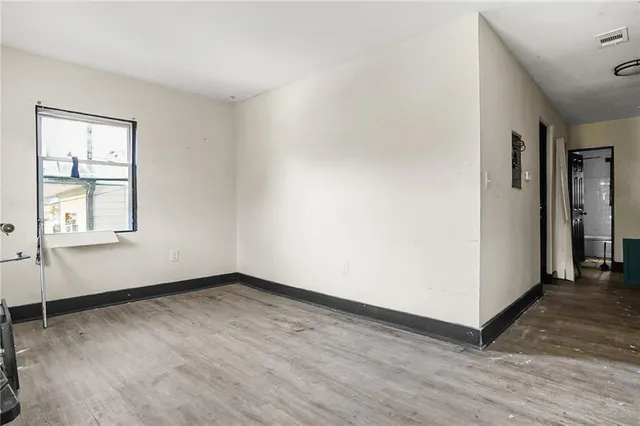 an empty room with wooden floor and windows