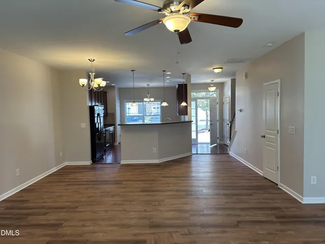 a view of an empty room with kitchen and a window