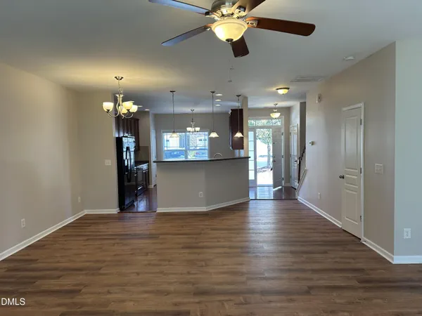 a view of an empty room with kitchen and a window