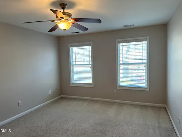 an empty room with a window and a fan
