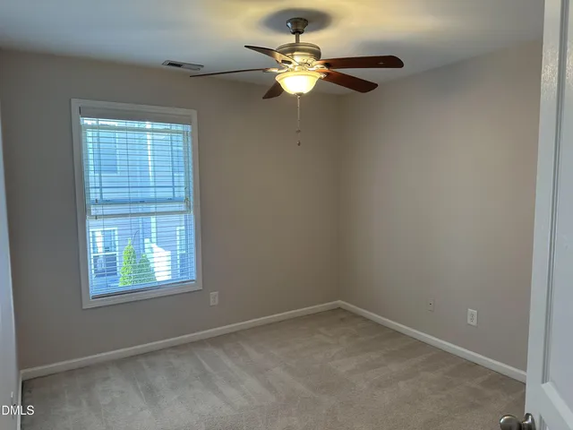 an empty room with a window and a fan
