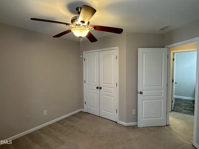 an empty room with closet and a chandelier fan