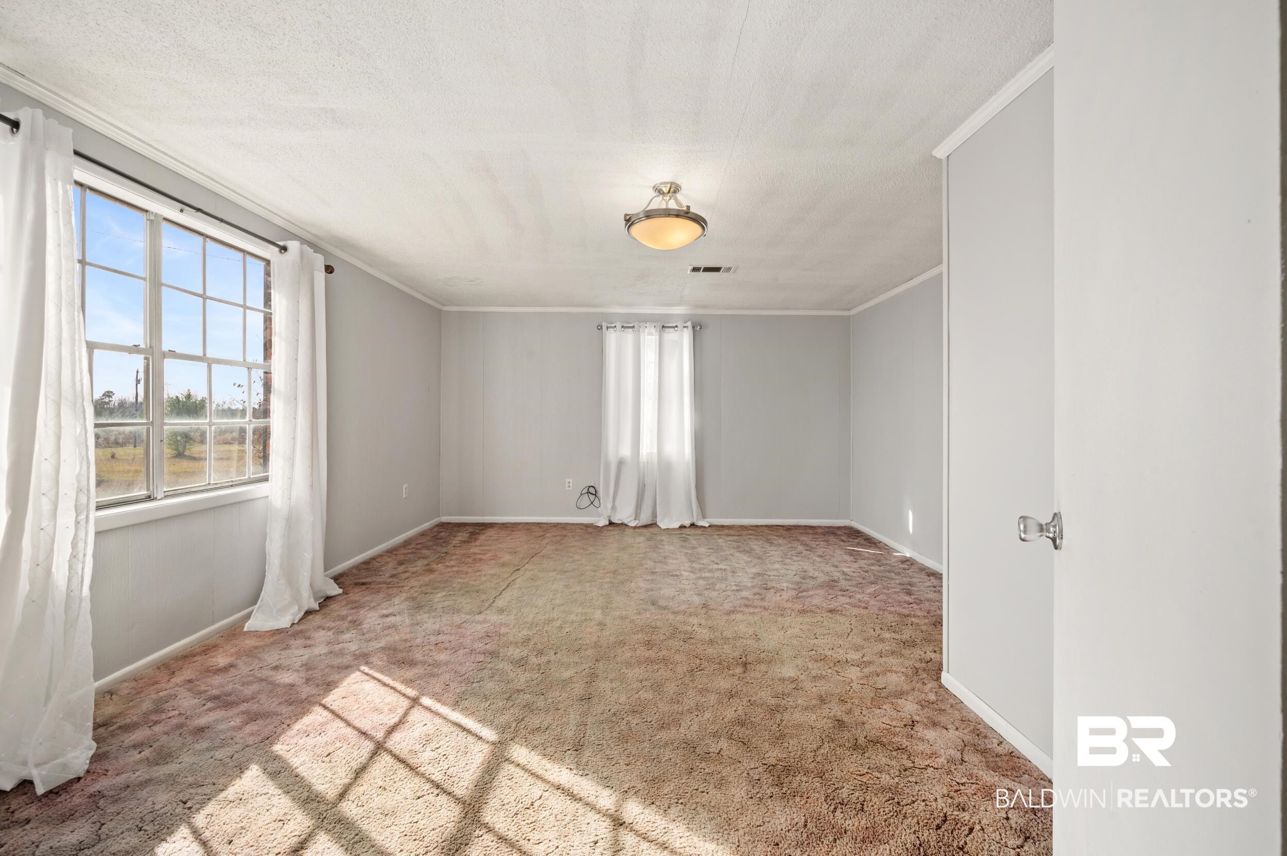 57623 Mary Hadley Road Perdido, AL 36562 - Photo 15 of 34 Spare room with light colored carpet, crown molding, and a textured ceiling