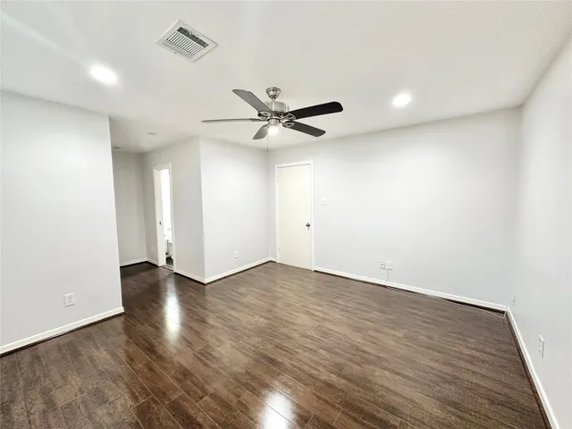 an empty room with wooden floor and ceiling fan